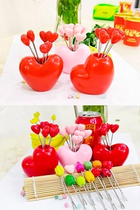 Macro detail of heart-shaped stainless steel fruit forks in red and pink holders