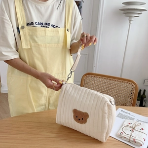 Close-up of quilted cotton makeup bag featuring a cute brown teddy bear embroidery