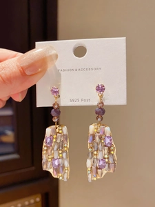 Detail of S925 silver needle earrings with purple crystal pendants and gold frame