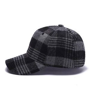 Close-up of grey and black plaid wool fabric texture and stitching on the baseball cap