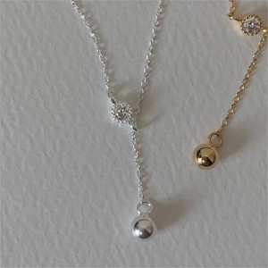 Detailed close-up of Y-shaped silver and gold necklaces with round zircon and metal ball drop