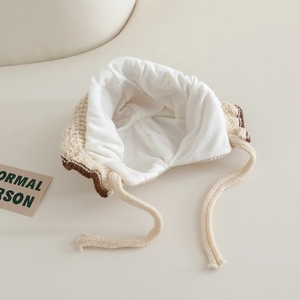Close-up of baby knit hat showing soft white inner lining and beige knitted texture