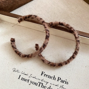 Macro view of leopard print plush hoop earrings with golden studs in vintage style