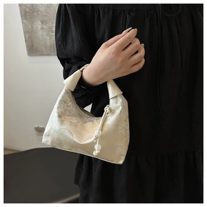Champagne silk handbag with vintage floral embroidery and bead pendant on a model