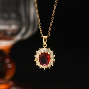 Close-up of golden necklace with oval red gemstone pendant and halo of clear zircons