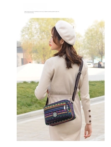 Outdoor shot of a striped ethnic canvas shoulder bag with adjustable strap and multiple pockets