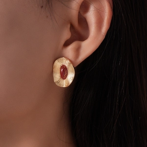 Gros plan sur boucle d'oreille vintage dorée avec pierre ovale rouge sur modèle
