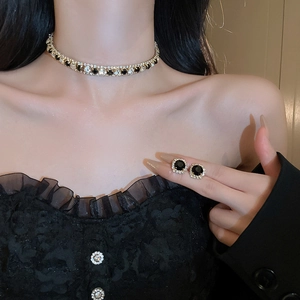 Vintage gold necklace and earring set with black stones worn by model in a chic style