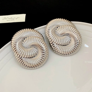 Detailed macro view of large silver geometric earrings with spiral sunburst texture