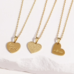 Detail of three gold titanium heart necklaces with Love You and Mom engravings