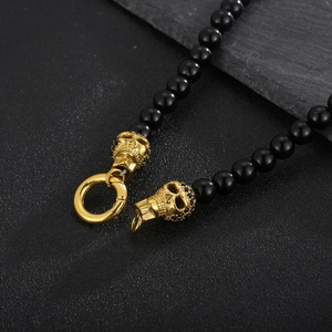 Macro shot of punk black beads and golden steel skulls on a textured stone base