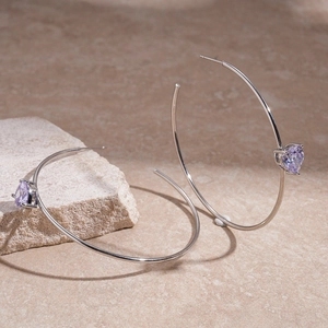 Detailed view of silver C-shaped hoop earrings with purple heart zirconia on textured stone