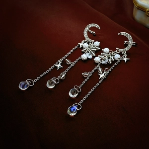 Detailed view of silver moon and star ear clips with sparkling tassel fringes and water drops