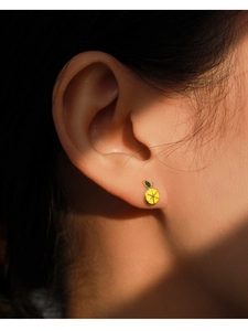 Macro detail of a lemon-shaped silver stud earring featuring vibrant yellow enamel and zircon