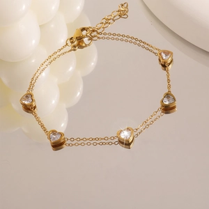 Dettaglio del bracciale a cuore dorato con cinque pietre di zircone scintillanti a cuore