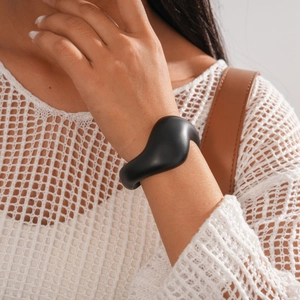 Detailed view of matte black irregular geometric open cuff bracelet on female wrist