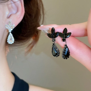 Detail view of drop earrings with leaf design and sparkling crystals in black and white