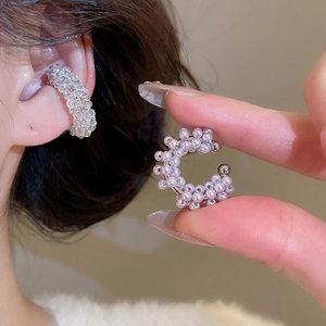 Detailed view of clear and purple beaded C-shaped ear cuffs on model's ear and hand
