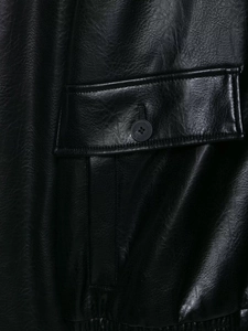 Detailed close-up of faux leather pilot jacket pocket with button and fine texture