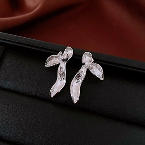 Close-up of silver abstract flower earrings with brushed metal texture on a black display