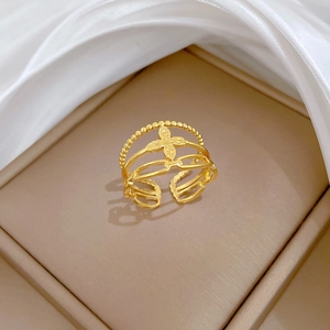 Detailed close-up of gold clover ring featuring layered chains on jewelry display box