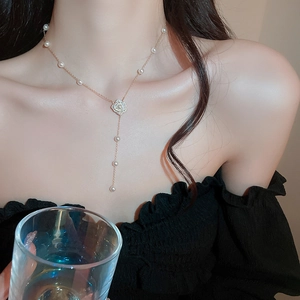 Détail d'un collier fleur en perle et zircon avec pampille élégante porté par un mannequin