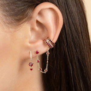 Close-up of 18K gold earring set with purple crystals on model ear for party look