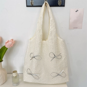 Dettaglio di una borsa tote beige a pois con fiocchi d'argento appesa a un gancio a muro