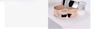 Close-up of minimalist mirror-finish bangles in silver and rose gold on a stone base