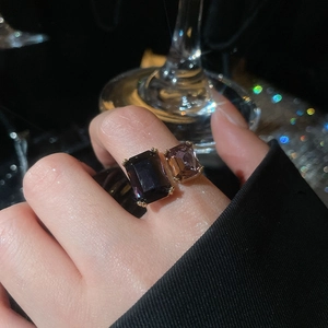 Detail of dual emerald cut purple zircon stones set on a luxury gold geometric ring