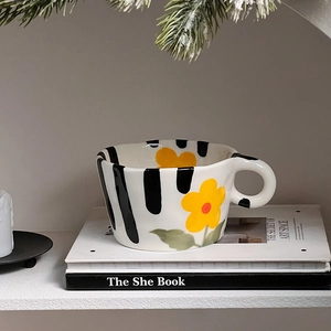 Detail of hand-pinched ceramic mug with hand-painted yellow flowers and black stripes
