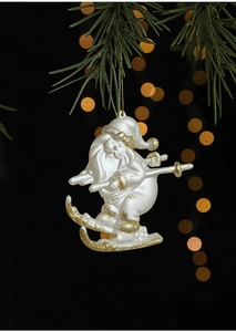 Vue détaillée du père Noël skieur blanc avec paillettes dorées sur branche de pin