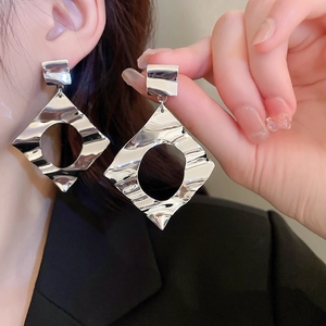 Close-up of silver geometric diamond earrings with a hammered water ripple texture
