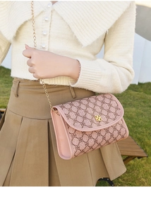 Sac bandoulière rose à motif floral avec chaîne dorée porté par un modèle en extérieur