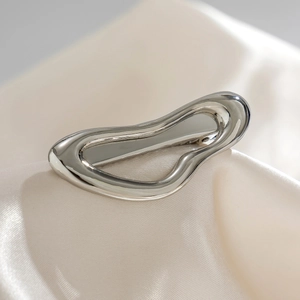 Macro detail of irregular silver metal hairpin on beige silk fabric with reflective finish