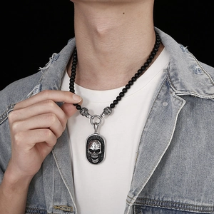 Close-up of gothic skull pendant on black agate beaded necklace for men's style