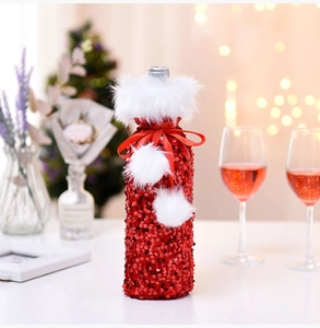 Close-up of red sequined Christmas wine bottle cover with white faux fur decor on table