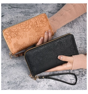 Detail of long women's wallet with floral embossing and detachable wrist strap in two colors
