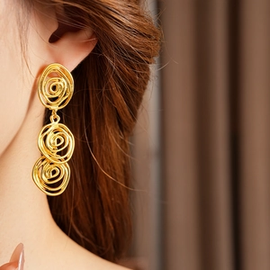 Detail of vintage gold-tone triple-loop swirl earrings worn by a model