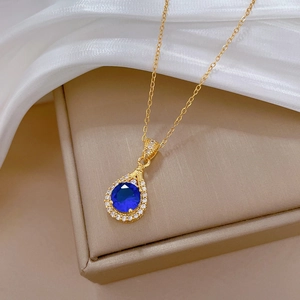 Detail of luxury teardrop necklace with deep blue gemstone on elegant white silk base