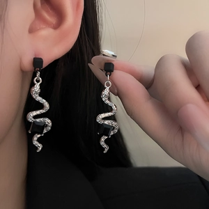 Détail macro d'une boucle d'oreille serpent argentée avec pierre carrée noire