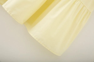 Detailed macro view of the light yellow cotton skirt hem showing soft fabric texture