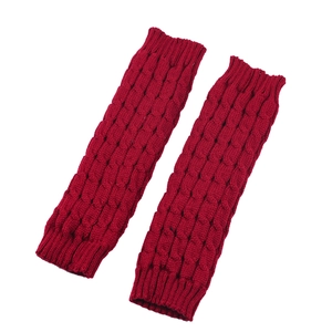 Detail of red cable-knit leg warmers with thick textured pattern and ribbed cuffs