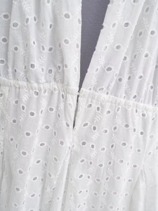 Dettaglio del ricamo bianco traforato e vita elastica sul vestito estivo all'americana