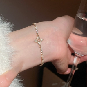 Detail of gold floral charm bracelet with sparkling zircons and elegant claw chain link