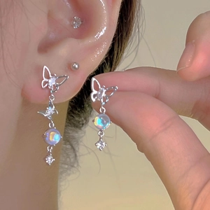 Macro view of silver butterfly earrings with iridescent beads on a female model