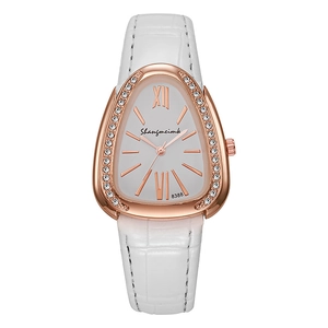 Close-up of rose gold snake-shaped watch with crystal bezel and white leather strap