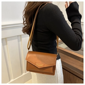 Detailed side view of brown PU leather crossbody bag with golden metal logo and strap