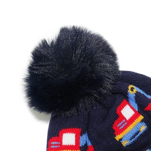 Detail of navy knit hat showing plush pom-pom and colorful excavator pattern for kids