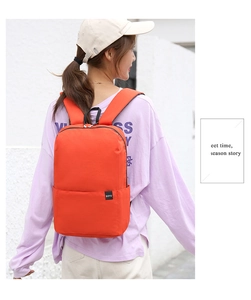 Detail of orange nylon backpack with BOYU tag shown on model against a white wall